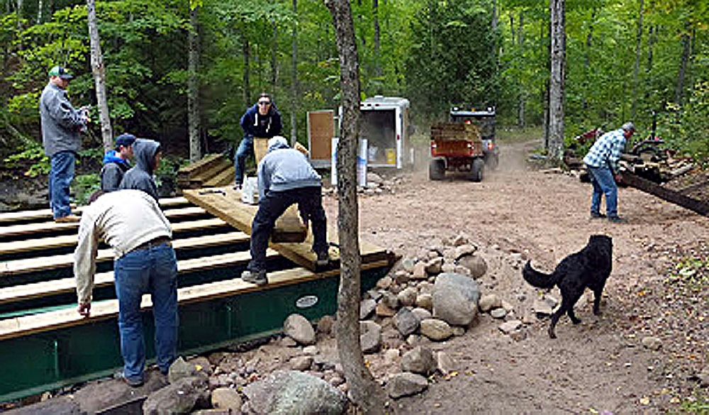 On Saturday, October 3rd, final work began on the new Swedetown Gorge Middle Bridge.  The order of the day was to install the wooden planking, atop the steel girders.  The longitudinal stringers had already been installed previously, so the work to attach the cross planking began. Helping were members of MTU Lambda Chi Allpha Fraternity. (KNSC photo).